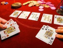 Cards on a red poker table with the flop and poker chips.