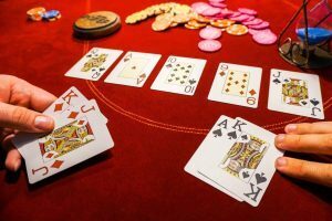 Cards on a red poker table with the flop and poker chips.