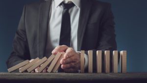 responsible gambling image of man in suit not letting the dominos fall