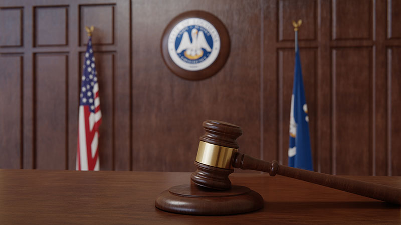 Courtroom scene with US flag and state seal and flag of the state of Louisiana.