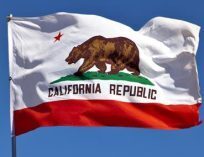 The California flag waving in the air. It features a red star, a brown bear and the words "California Republic".