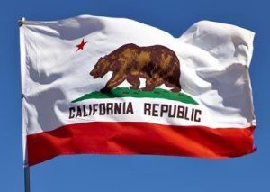 The California flag waving in the air. It features a red star, a brown bear and the words "California Republic".