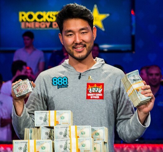 2018 WSOP Main Event Champion John Cynn holding cash and the Main Event bracelet.