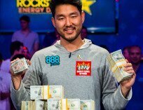 2018 WSOP Main Event Champion John Cynn holding cash and the Main Event bracelet.