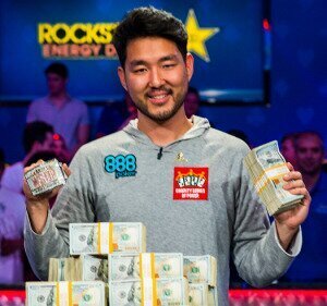 2018 WSOP Main Event Champion John Cynn holding cash and the Main Event bracelet.