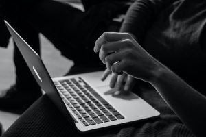 Hands typing on an Apple Macbook. Black and White filter on the photo.