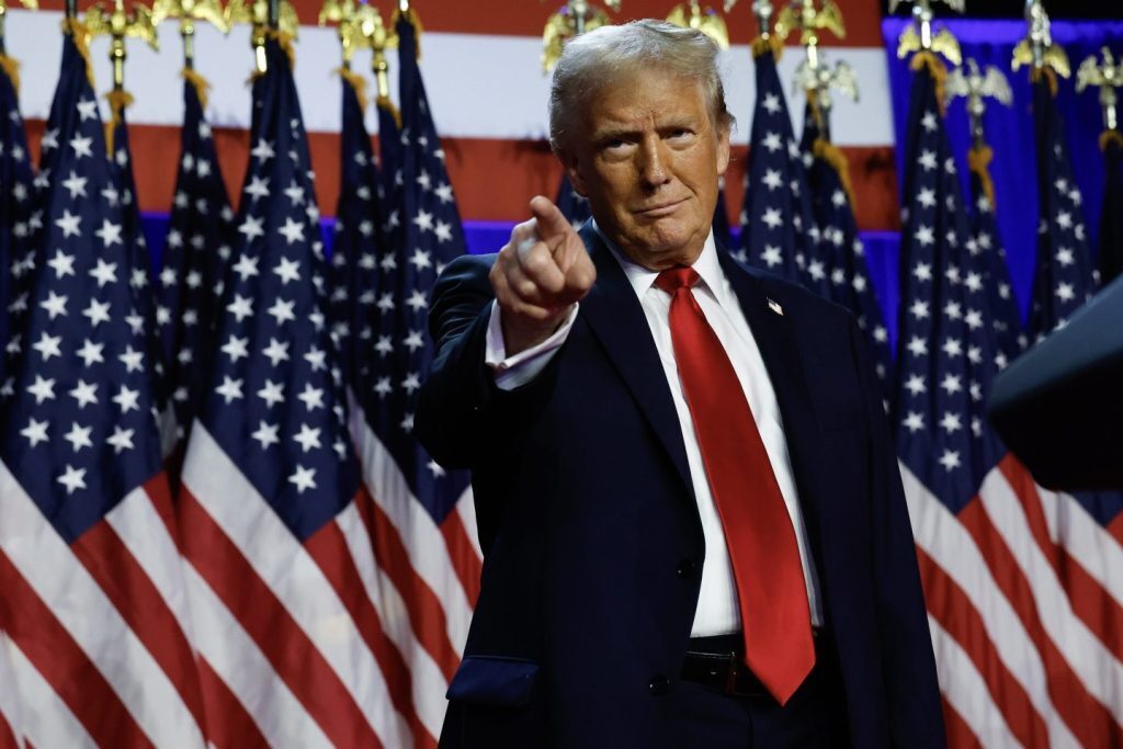 Donald Trump pointing with flags behind him