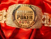 Close-up of a gold World Series of Poker (WSOP) championship bracelet encrusted with diamonds, resting on red satin fabric.