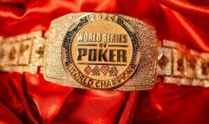 Close-up of a gold World Series of Poker (WSOP) championship bracelet encrusted with diamonds, resting on red satin fabric.