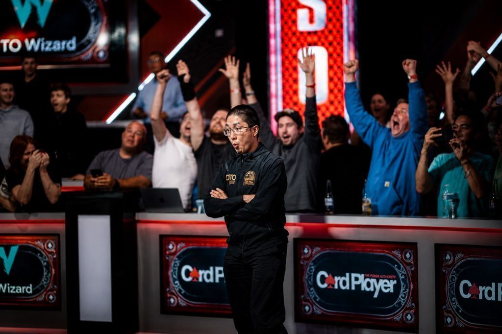 Jonathan Tamayo reacting at the WSOP final table while the crowd celebrates behind him during a key tournament moment.
