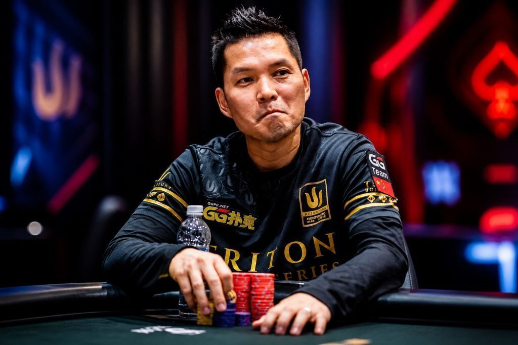 Tony “Ren” Lin sitting at a poker table during a Triton tournament, focused with chips stacked in front of him and a blurred, neon-lit background.