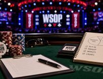 WSOP poker table setup with tournament chips, staking paperwork, payout notes, and a notebook showing backer percentages during a World Series of Poker event.