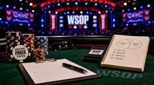 WSOP poker table setup with tournament chips, staking paperwork, payout notes, and a notebook showing backer percentages during a World Series of Poker event.