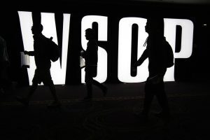 Three players walk in front of a WSOP sign carrying poker chips