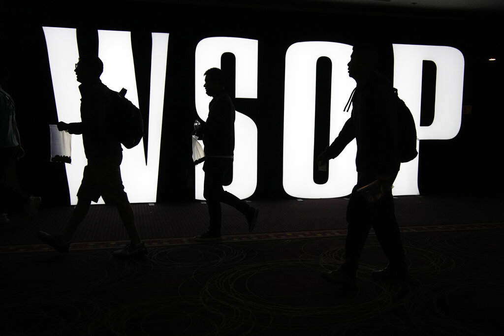 Three players walk in front of a WSOP sign carrying poker chips