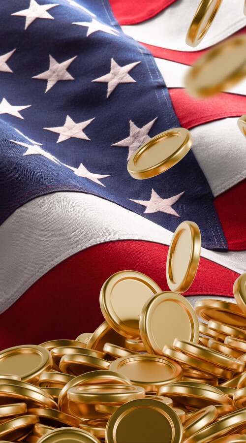 Gold coins falling onto a pile against a waving American flag.